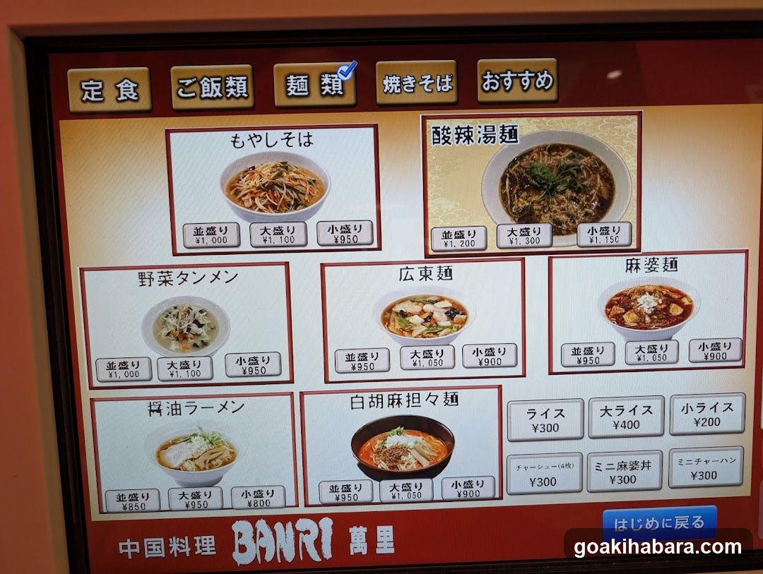 A digital menu display showing various noodle dishes and rice options with prices in yen.