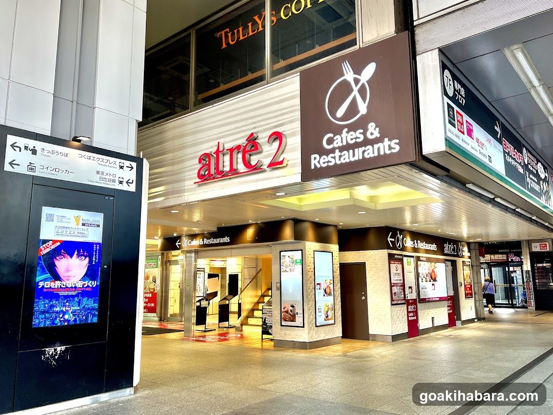Exterior view of the atré 2 cafe and restaurant chain, featuring signage with a fork and spoon logo above the entrance. The storefront includes illuminated signs reading 'Cafes & Restaurants' and displays posters advertising food items.