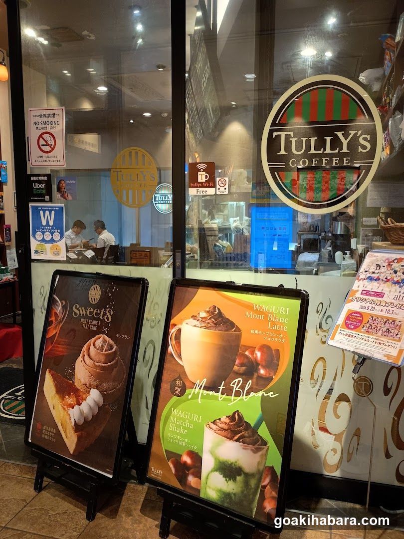 Photo of Tully's Coffee exterior entrance with visible signage on the building, including a circular logo and interior view through glass doors.