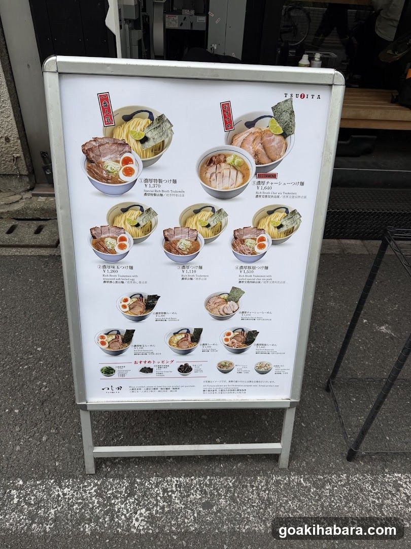 A standing menu board displaying various ramen dishes with images and descriptions in Japanese.