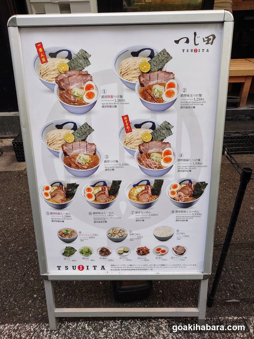 A standing menu board displaying various ramen dishes with images, names, and prices in Japanese and English.