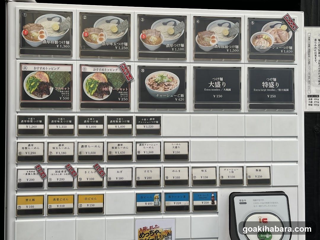 A close-up of a ramen vending machine menu board displaying various noodle soup options with prices in yen.