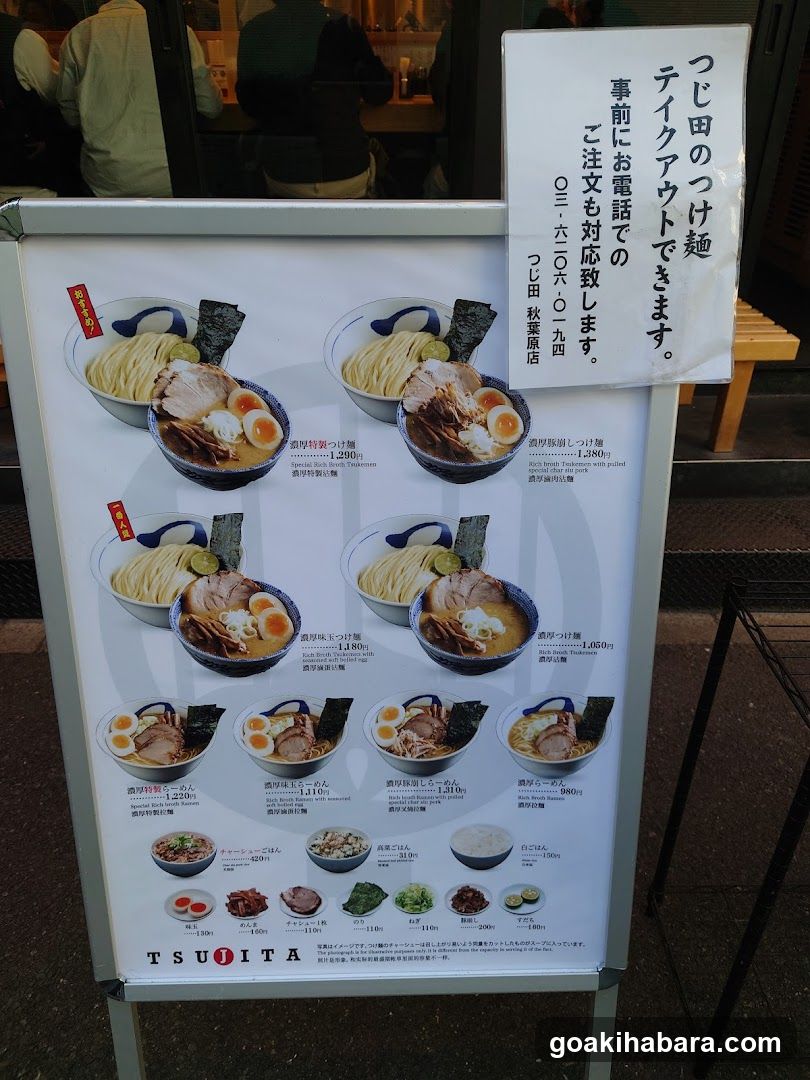 A menu board displaying various ramen dishes with prices and descriptions, along with a notice about phone orders.