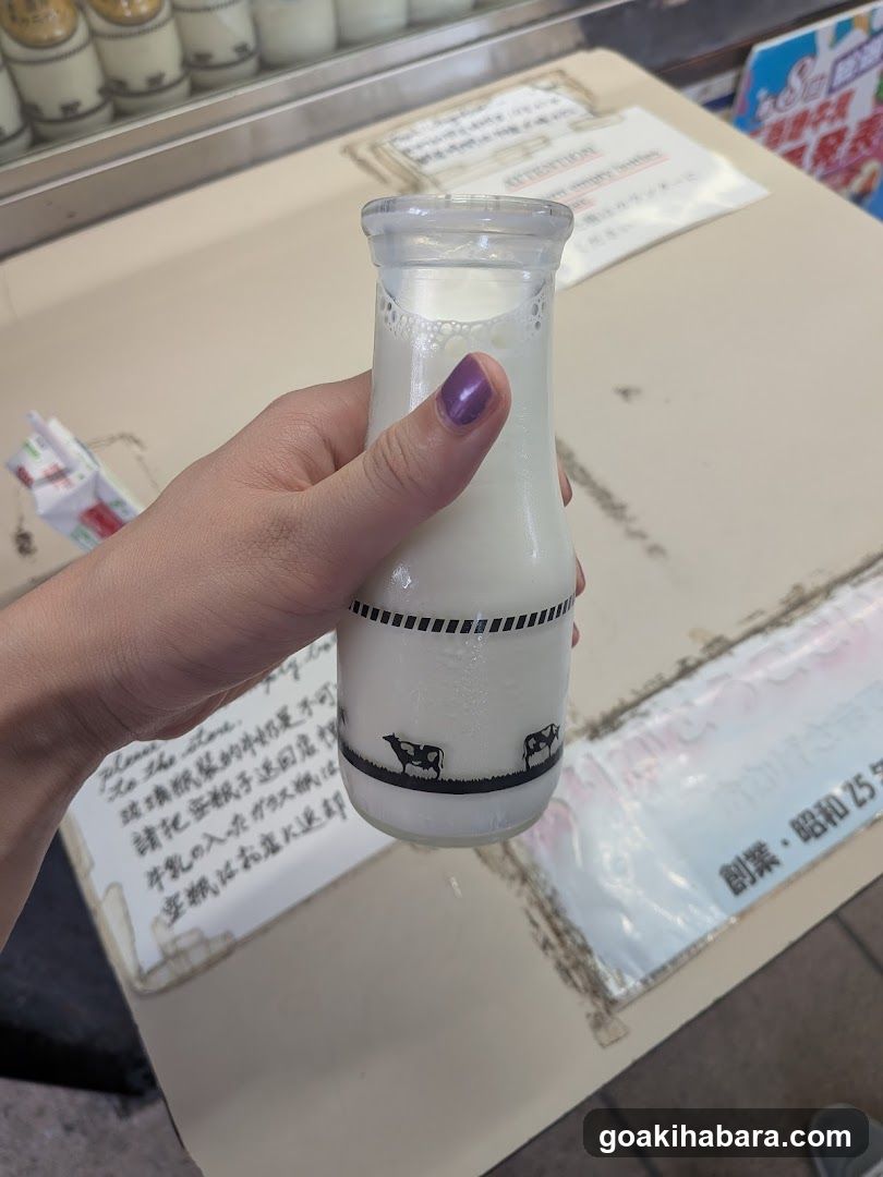 Hand holding milk bottle at shop counter