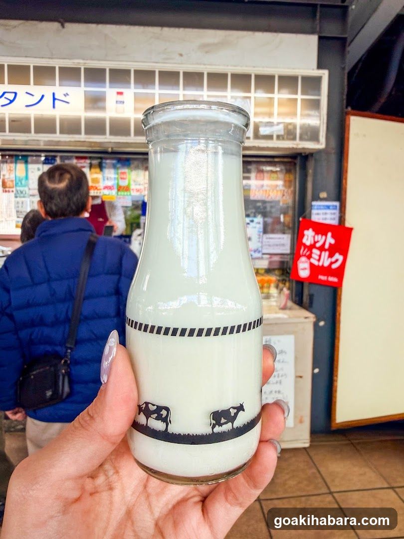 Hand holding milk bottle in front of shop