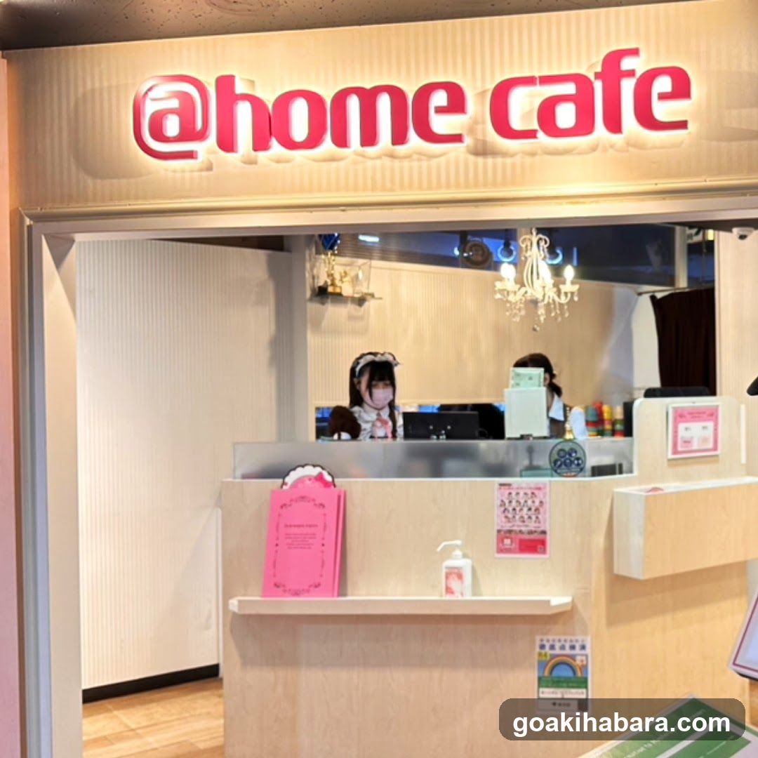 Photo of the physical entrance to @home cafe, showing illuminated signage above a service counter with staff behind and promotional materials on display.