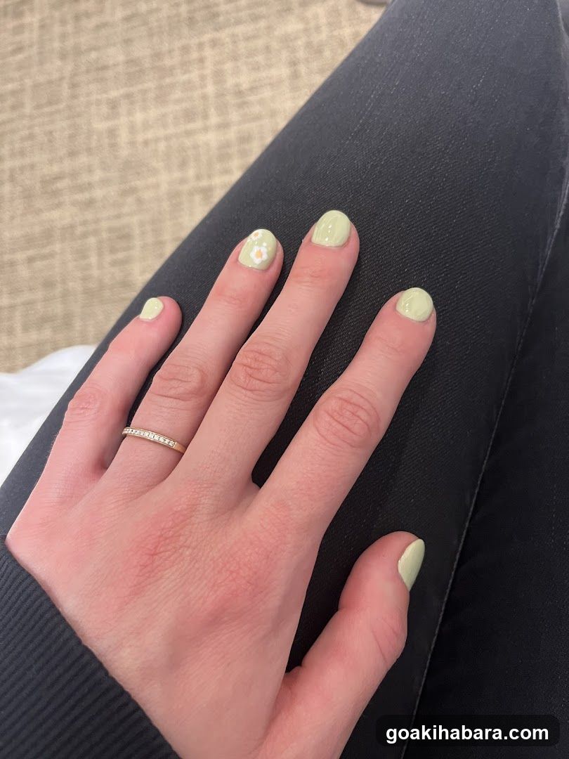 Hand with light green nail polish and ring