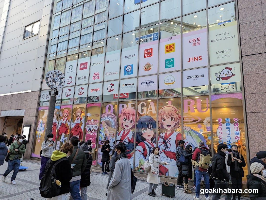 Anime-themed storefront with large character posters and multiple brand signs on glass facade.