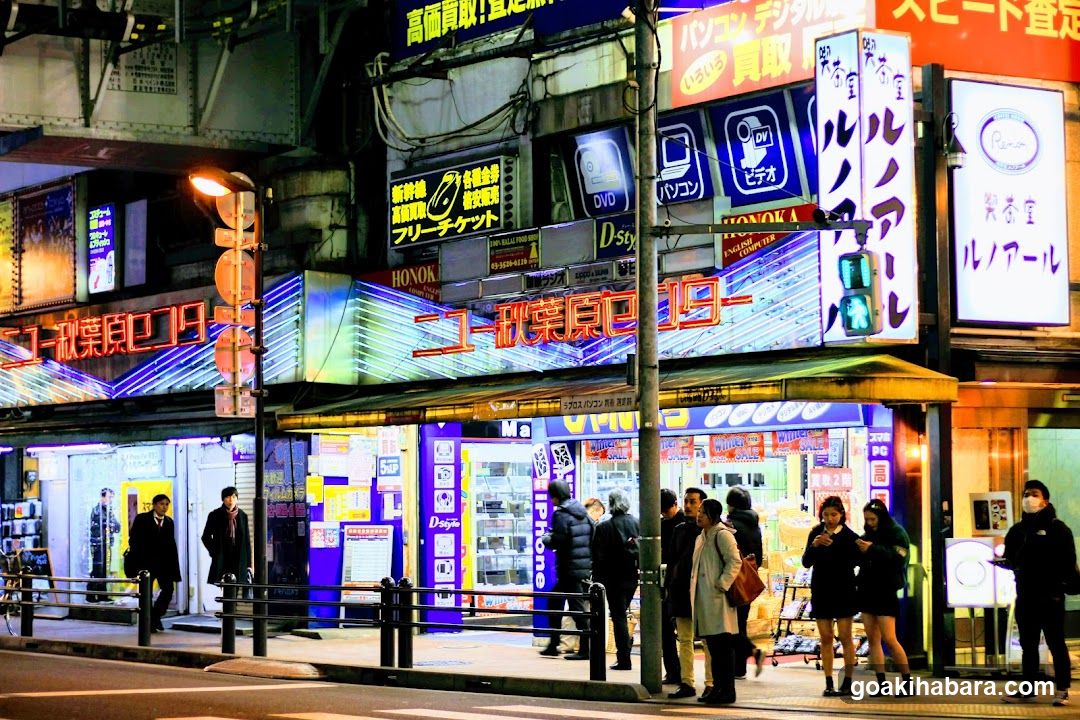 Night street scene with illuminated storefronts and pedestrians