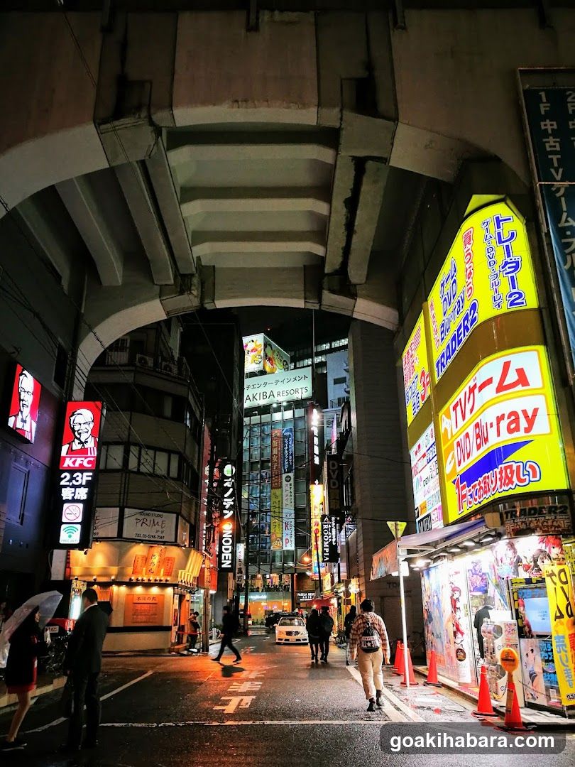 Night street scene under overpass with illuminated signs and pedestrians
