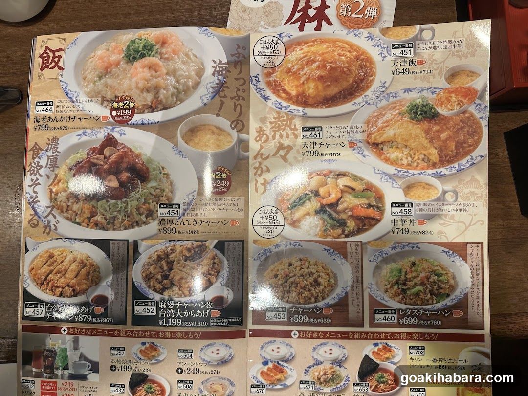 A close-up of a Japanese restaurant menu featuring various rice dishes, including curry rice, fried chicken, and omelet rice. The menu includes prices in yen and some English descriptions.