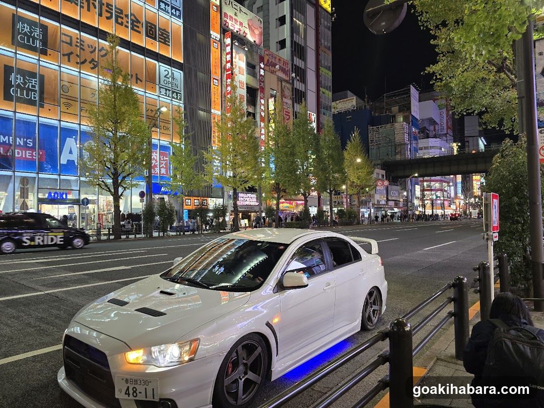 Night street scene with white car and illuminated buildings