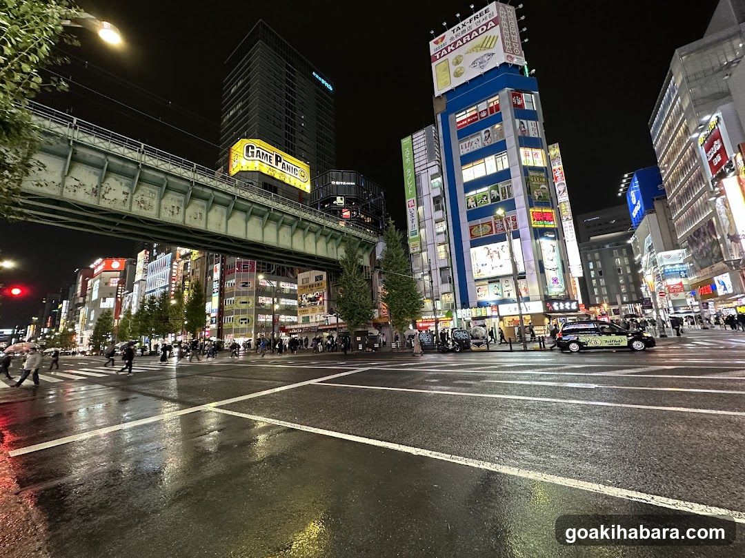 Night street scene with illuminated buildings and wet pavement