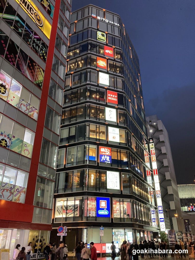 Night view of a modern commercial building with illuminated signage and storefronts.