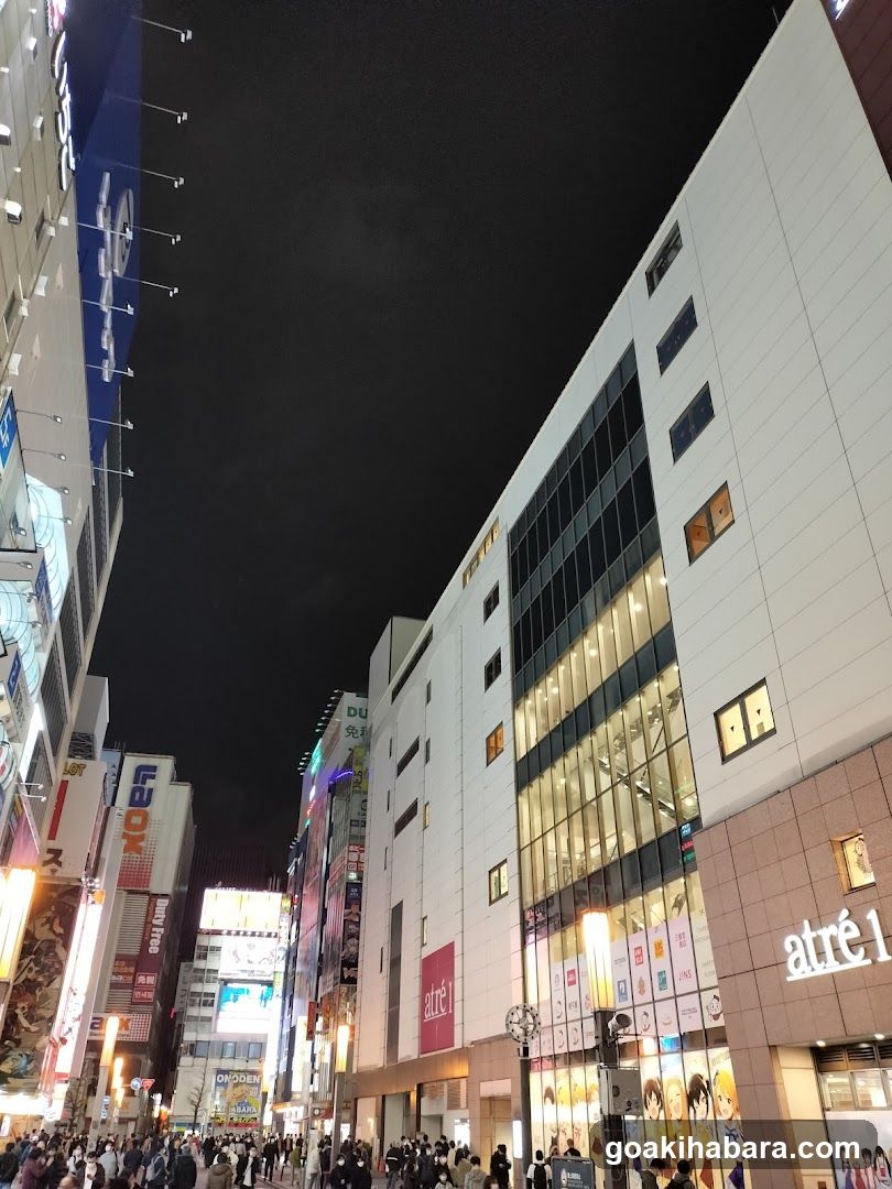 Night street scene with illuminated buildings and crowds