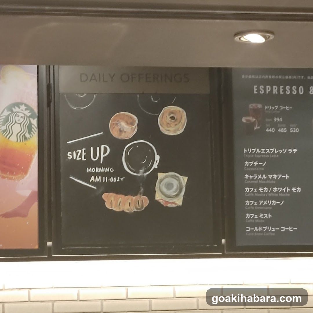 Photo of a Starbucks storefront featuring a window display with 'DAILY OFFERINGS' and 'SIZE UP MORNING AM 11-00' signage, alongside illustrations of pastries and coffee cups. A partial menu board on the right lists espresso drinks in Japanese.