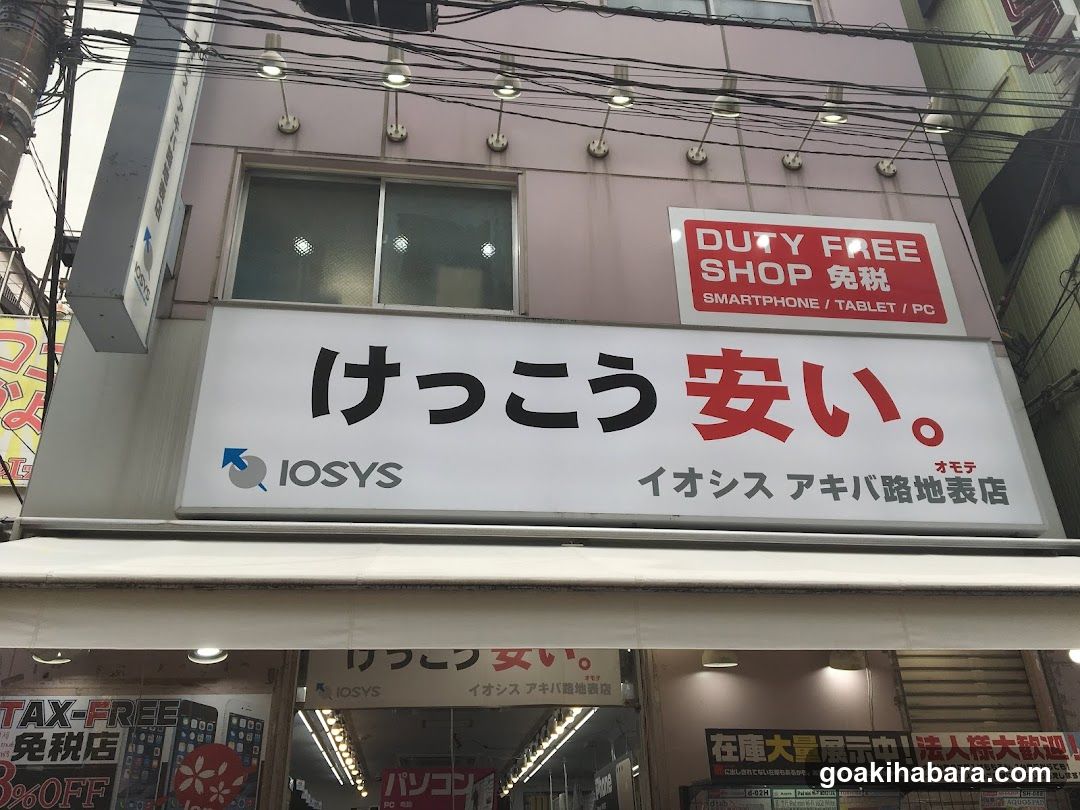 A shop front with a large white sign displaying Japanese characters and the word 'cheap' in red. Above it, there is a smaller red sign indicating 'DUTY FREE SHOP'. The building has multiple lights attached to its facade.