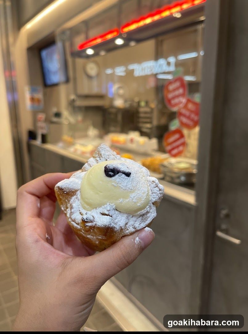 Hand holding a powdered pastry in front of a bakery counter