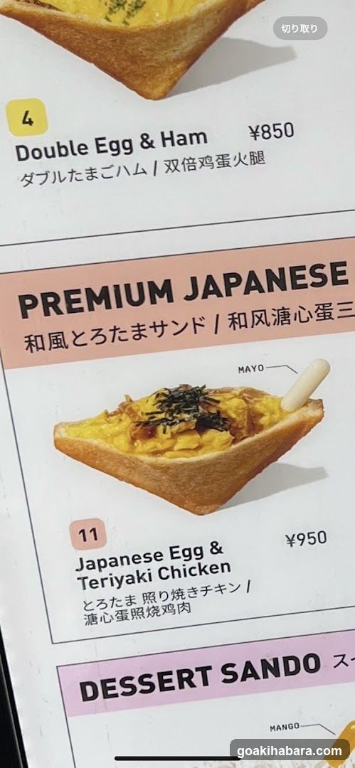 A close-up of a printed menu page featuring sandwich items with English, Japanese, and Chinese descriptions.