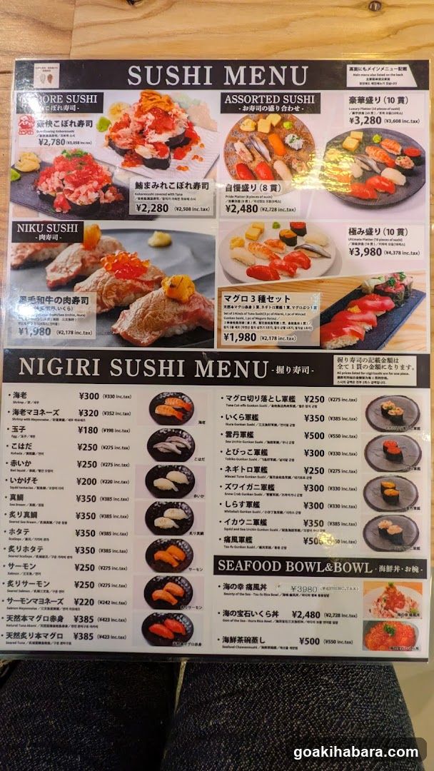 A printed sushi menu featuring sections for Sashimi, Assorted Sushi, Niku Sushi, and a detailed list of nigiri items with prices in yen.