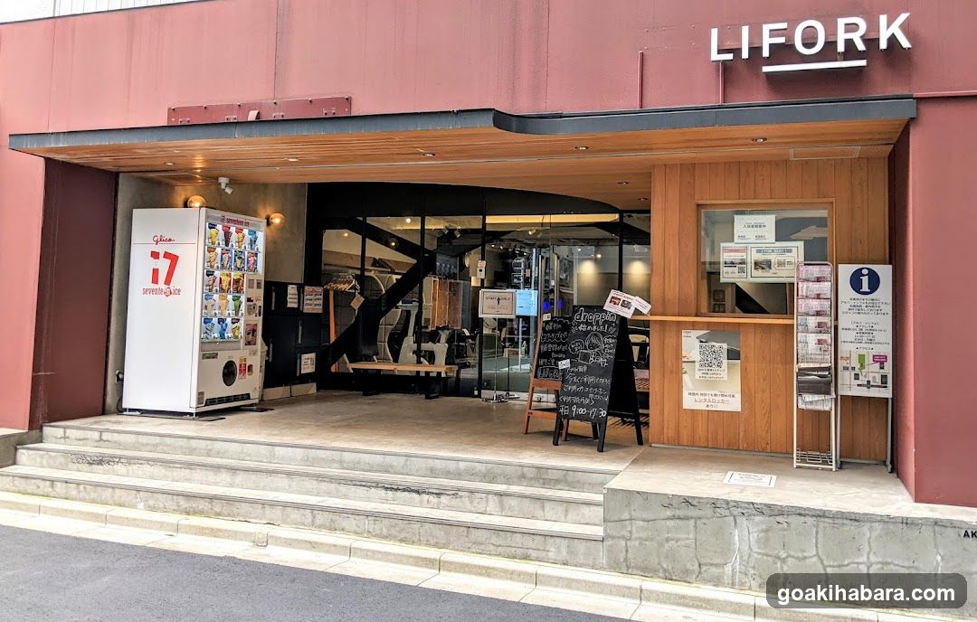 Exterior view of LIFORK shop with visible signage, vending machine, chalkboard menu board, and glass doors leading to interior.